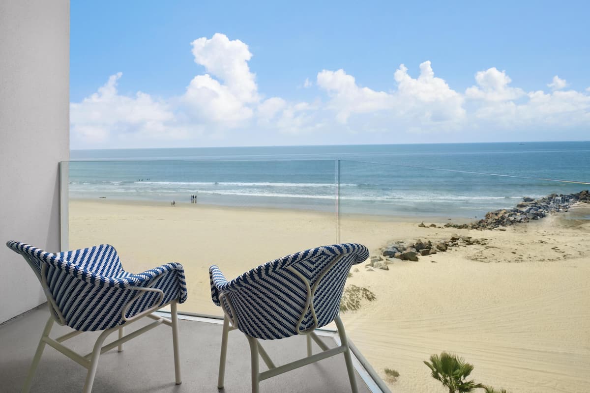 Un balcon avec deux chaises donnant sur une plage.