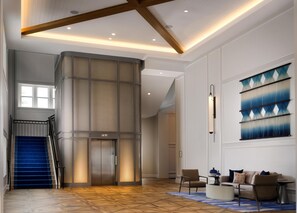 A spacious lobby with a staircase, elevator, and a seating area with a coffee table.