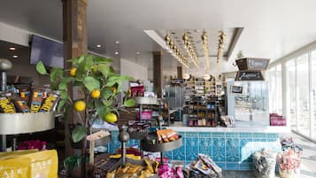 Una panadería con una variedad de productos horneados y pasteles a la vista, un letrero de inscripción y un amplio ventanal que proporciona luz natural.