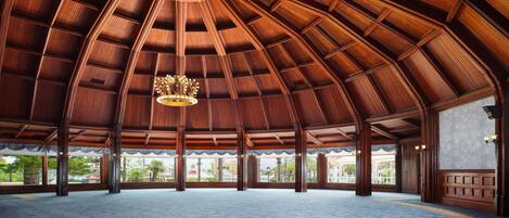 A spacious hall with a high wooden ceiling and a central chandelier.