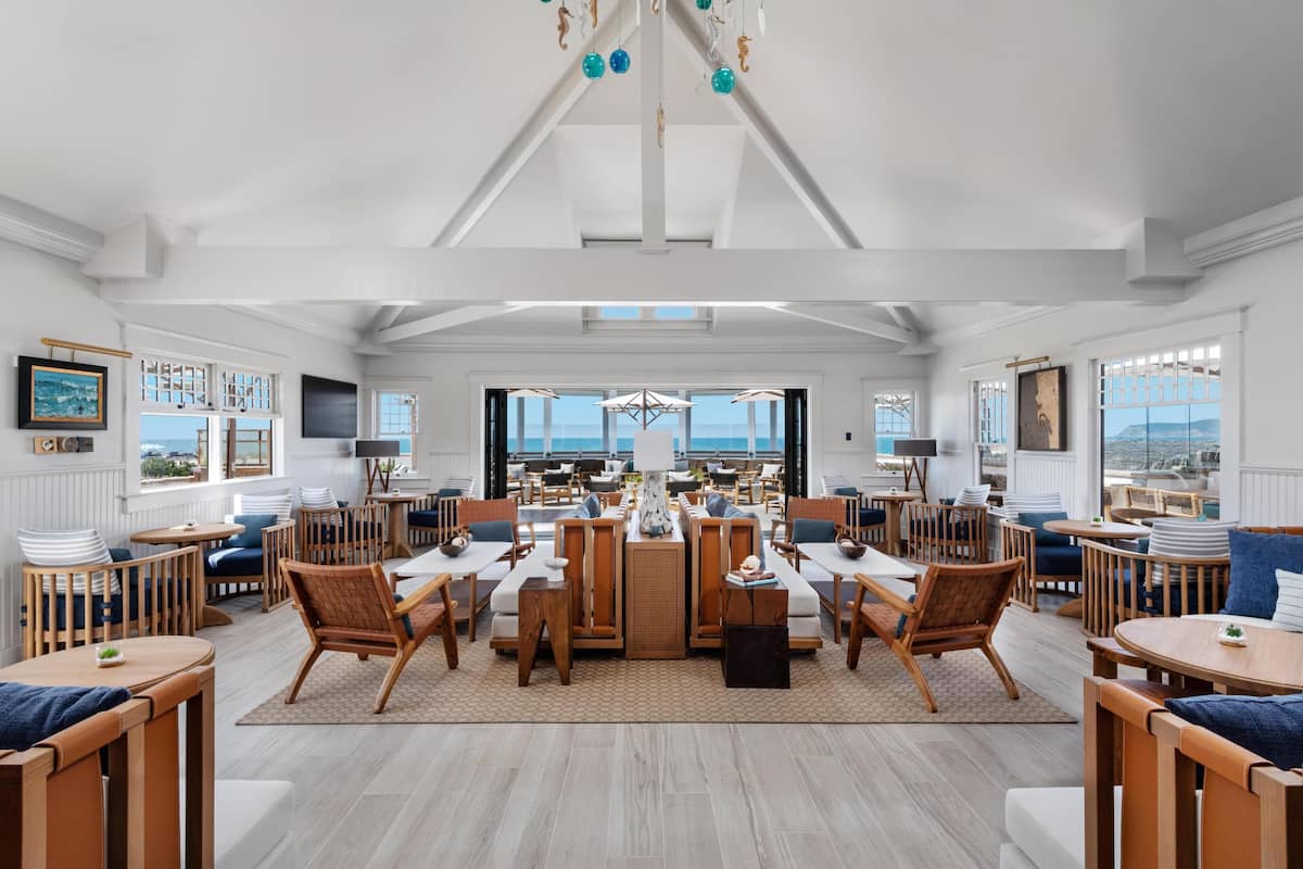 Une pièce spacieuse dotée d’une grande table à manger, de plusieurs coins salon et offrant une vue sur l’océan.