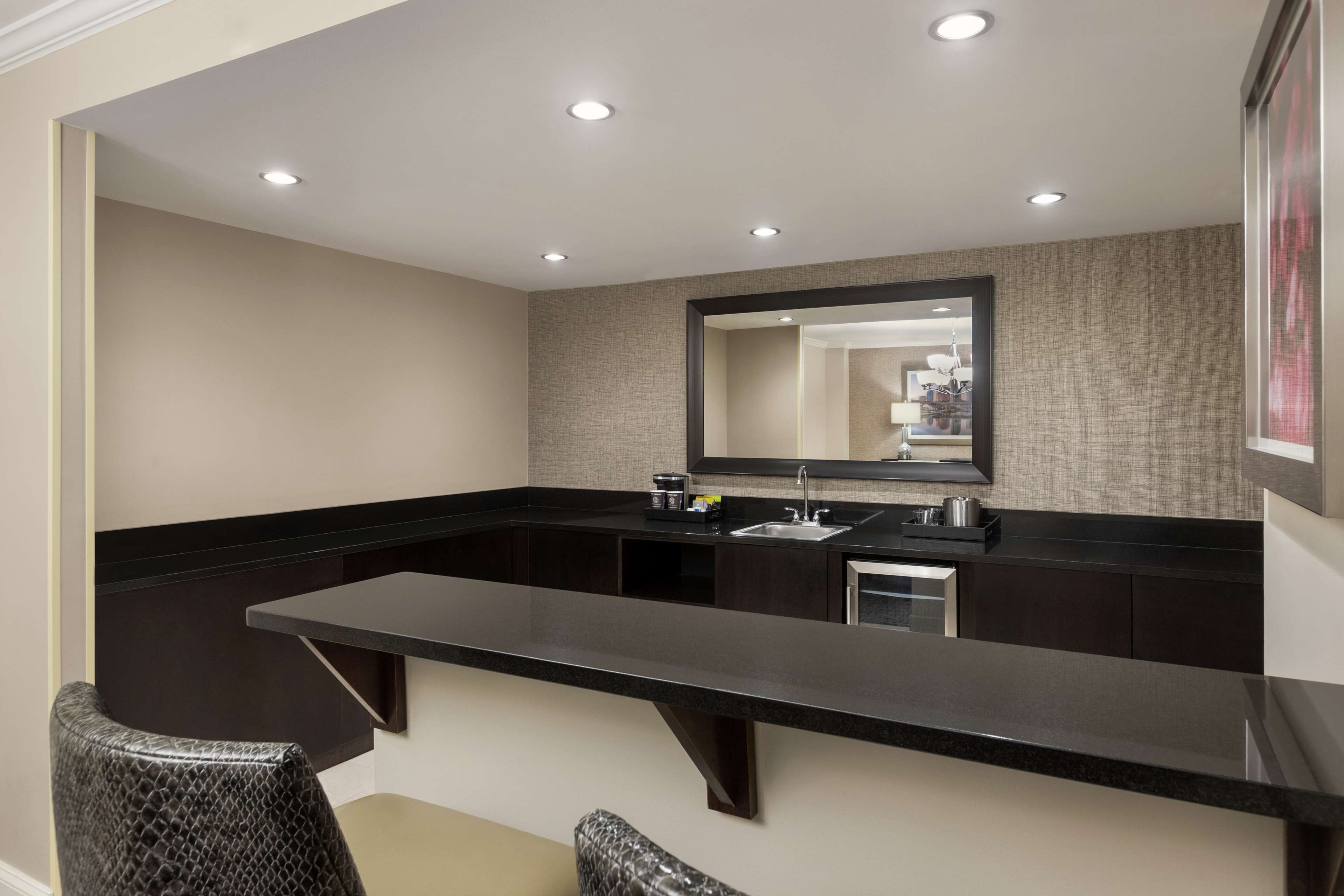 A modern bathroom with a large mirror, dark countertops, and a sink.