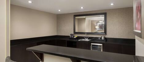 A modern bathroom with a large mirror, dark countertops, and a sink.