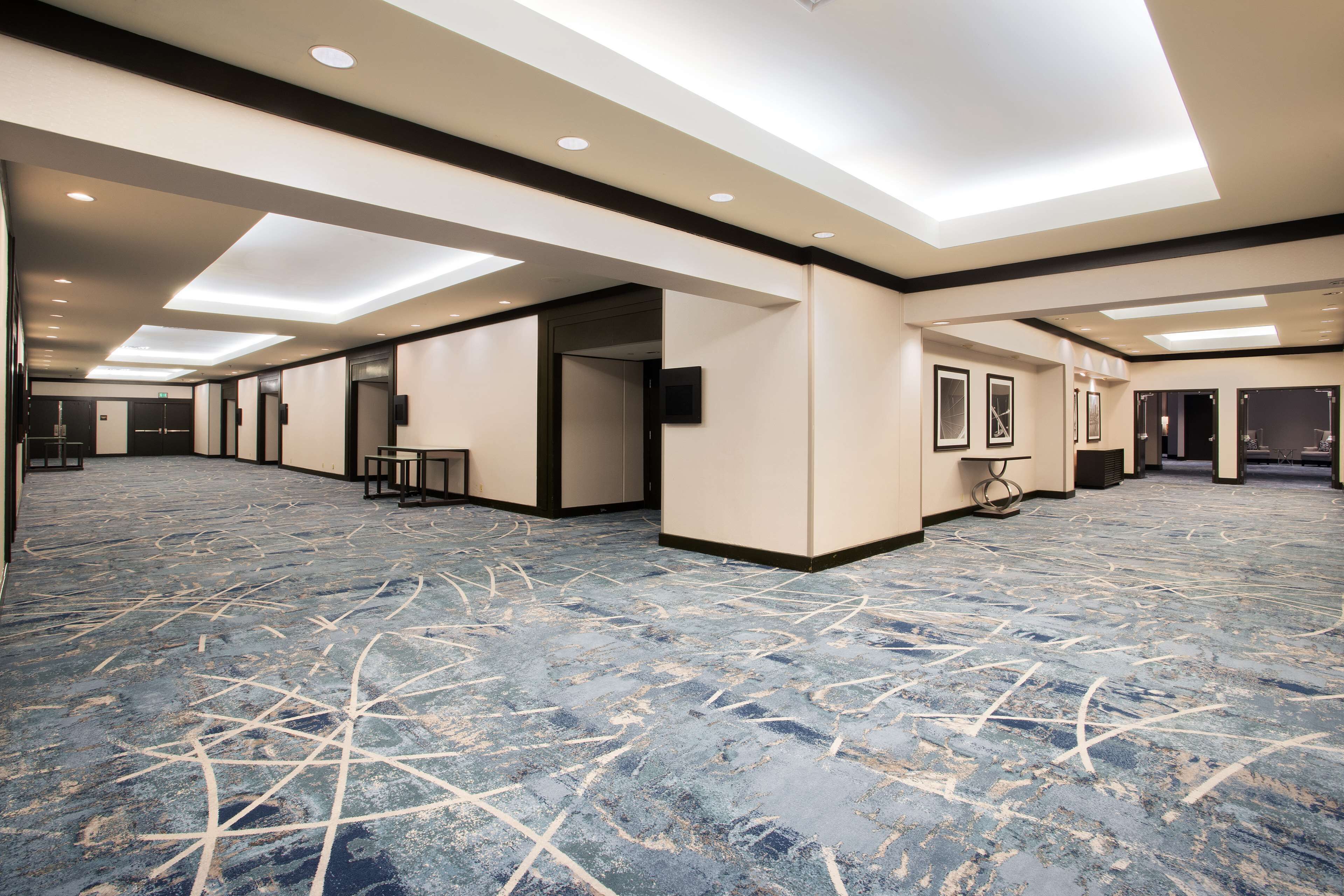 A spacious hotel lobby with a patterned carpet, recessed lighting, and a modern design.