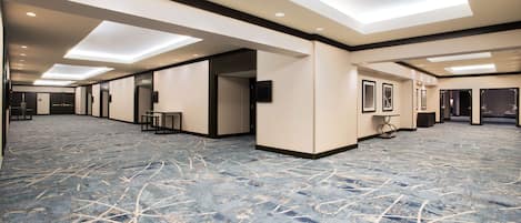 A spacious hotel lobby with a patterned carpet, recessed lighting, and a modern design.