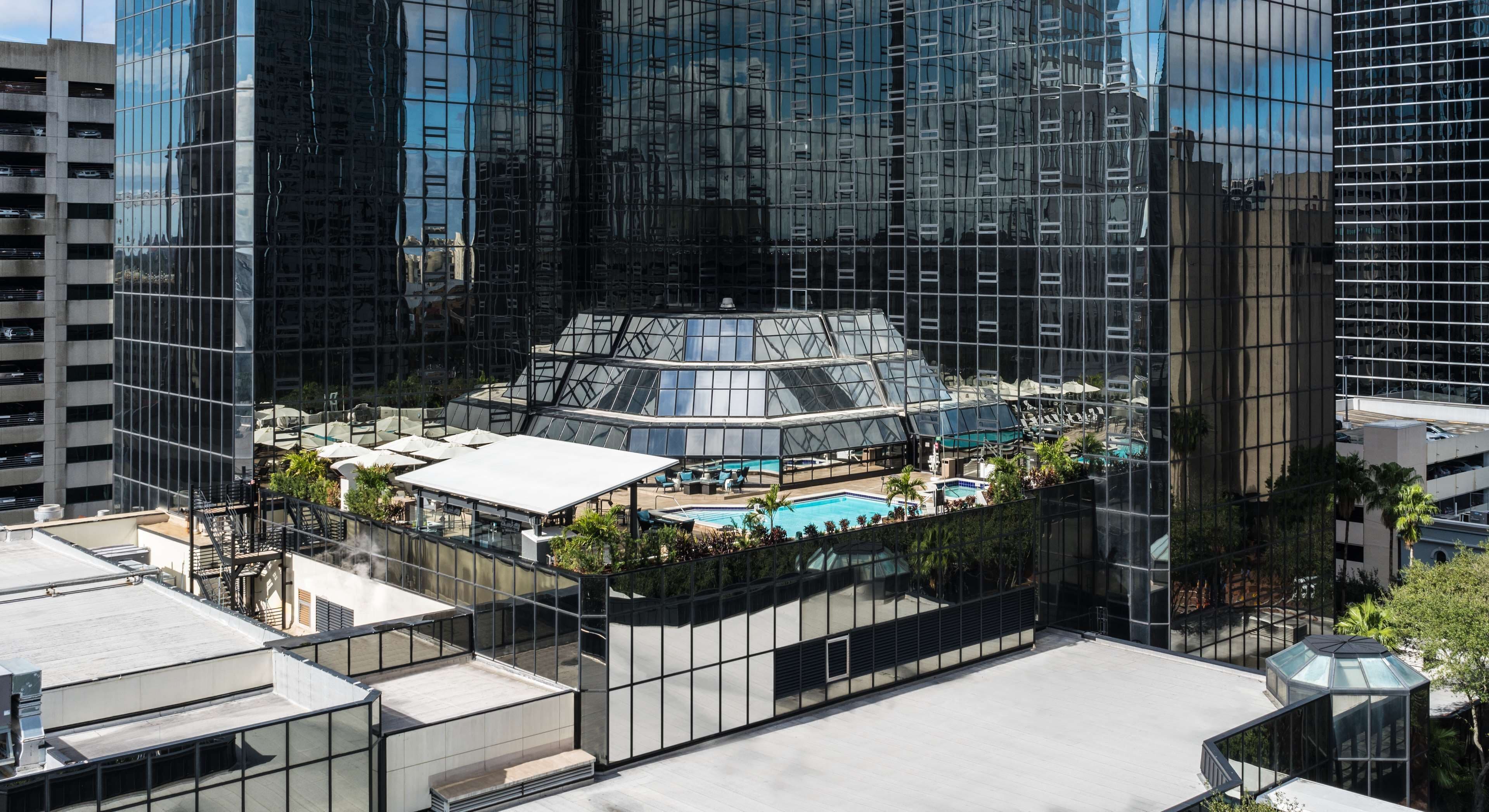 A modern hotel with a rooftop pool, surrounded by high-rise buildings.