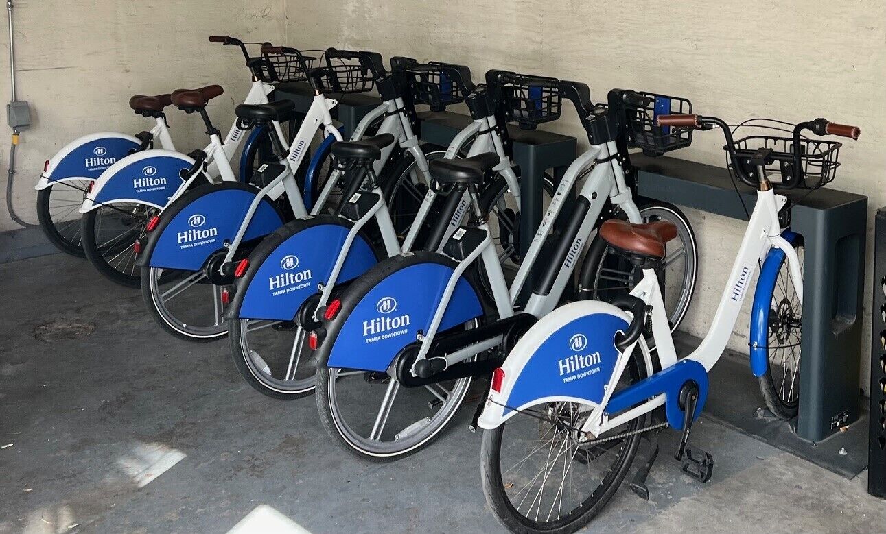 A row of bicycles branded with 'Hilton' in a docking station area.