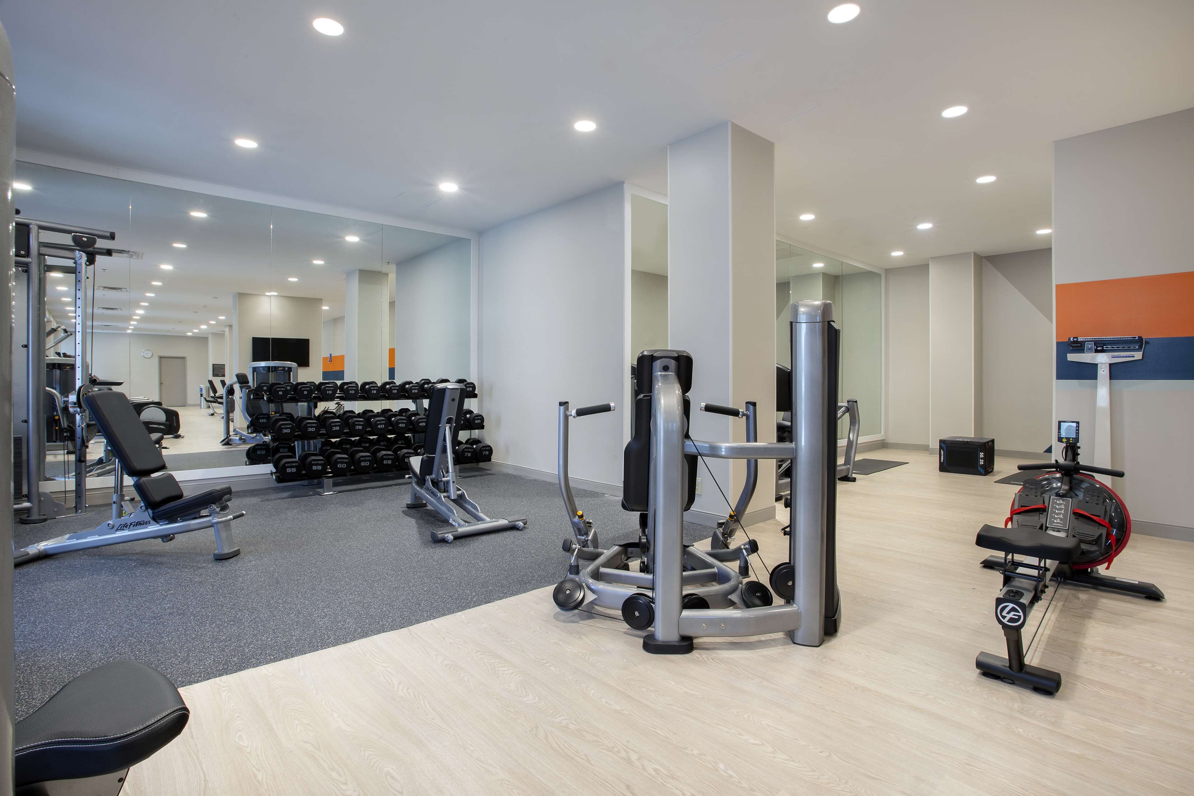 A gym with various exercise equipment, including dumbbells, a bench, and a stationary bike.
