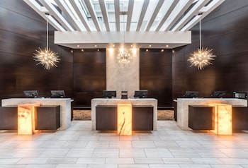 A spacious restaurant with high ceilings, large windows, and a variety of seating arrangements including round tables and wooden chairs. at Hilton Tampa Downtown