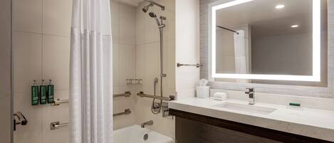 A modern bathroom with a bathtub, shower, and a large mirror above the sink.