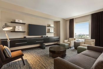 A hotel room with a large bed, a desk with a chair, a TV, and a view of the city. at Hilton Tampa Downtown