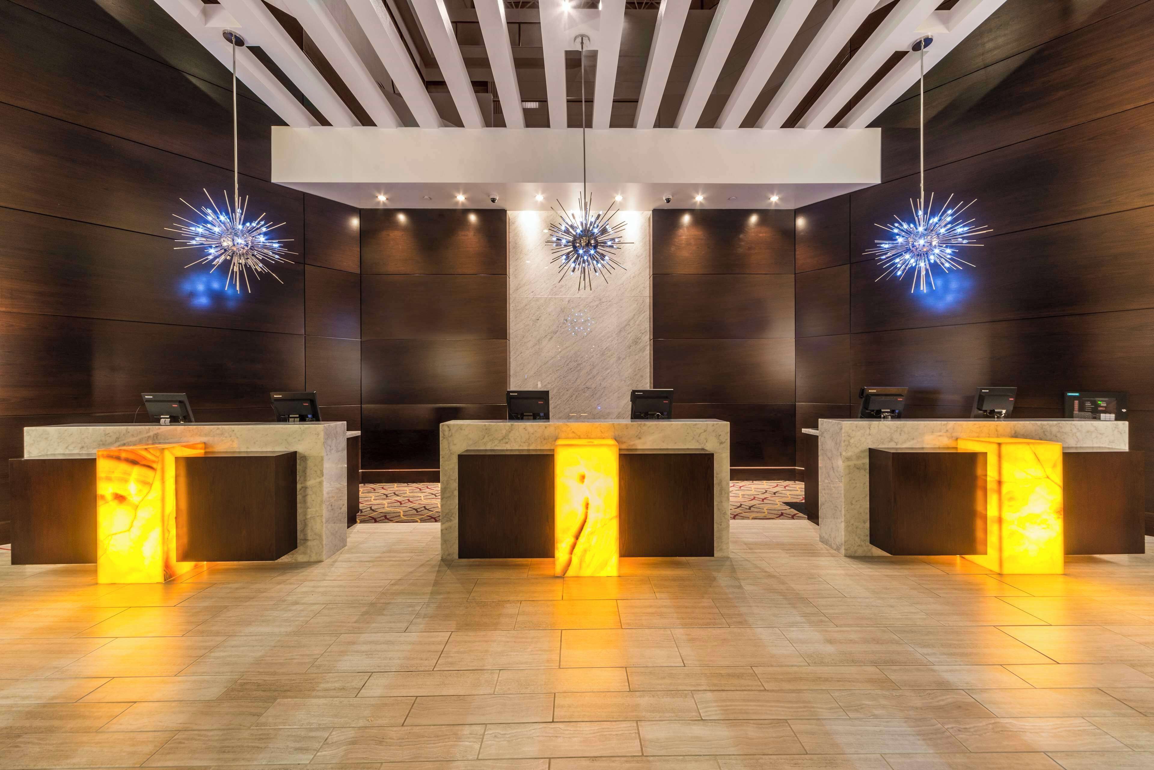 A reception area with three counters, each with a glowing base and a star-shaped light fixture above.