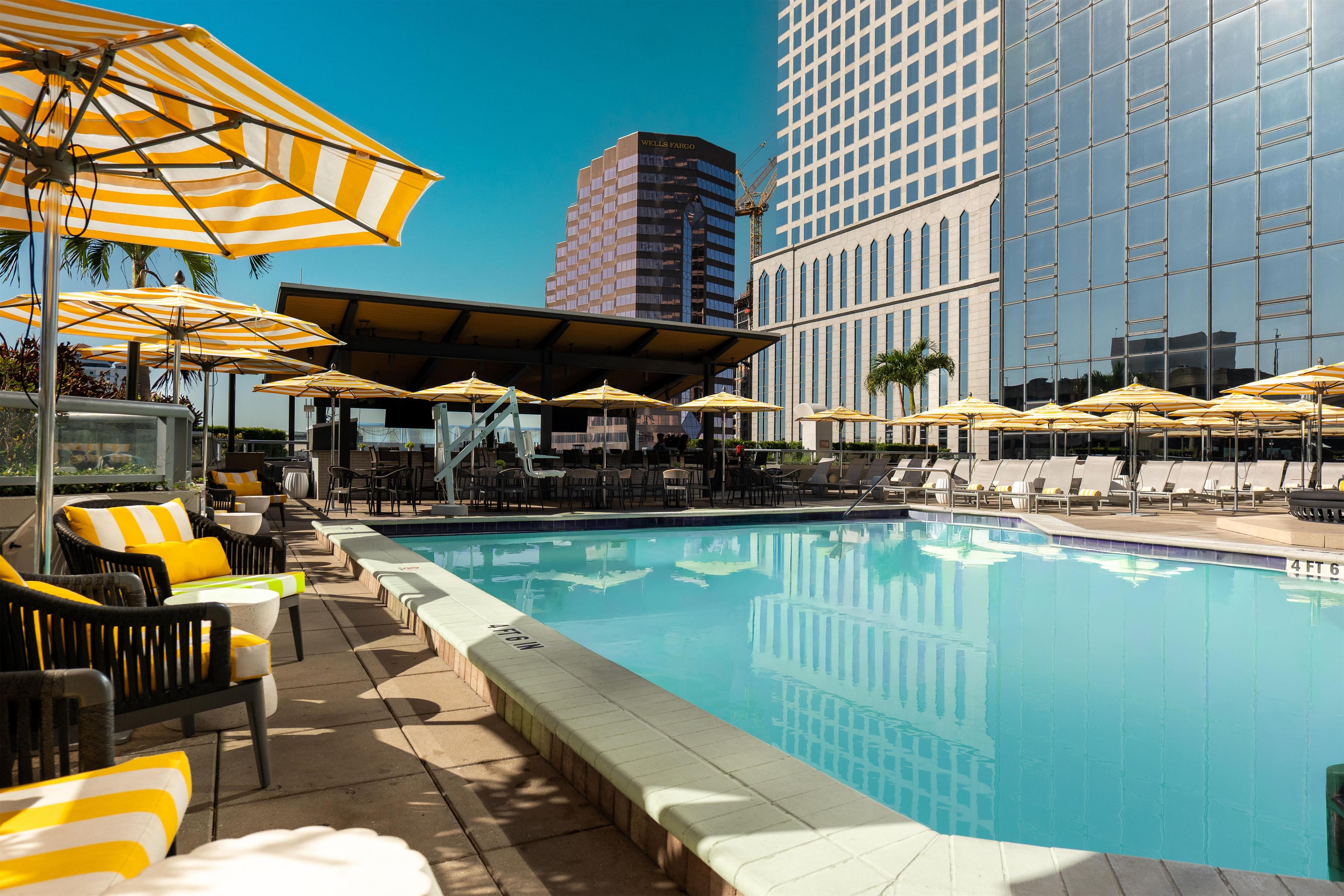 A pool area with lounge chairs and umbrellas, surrounded by buildings.