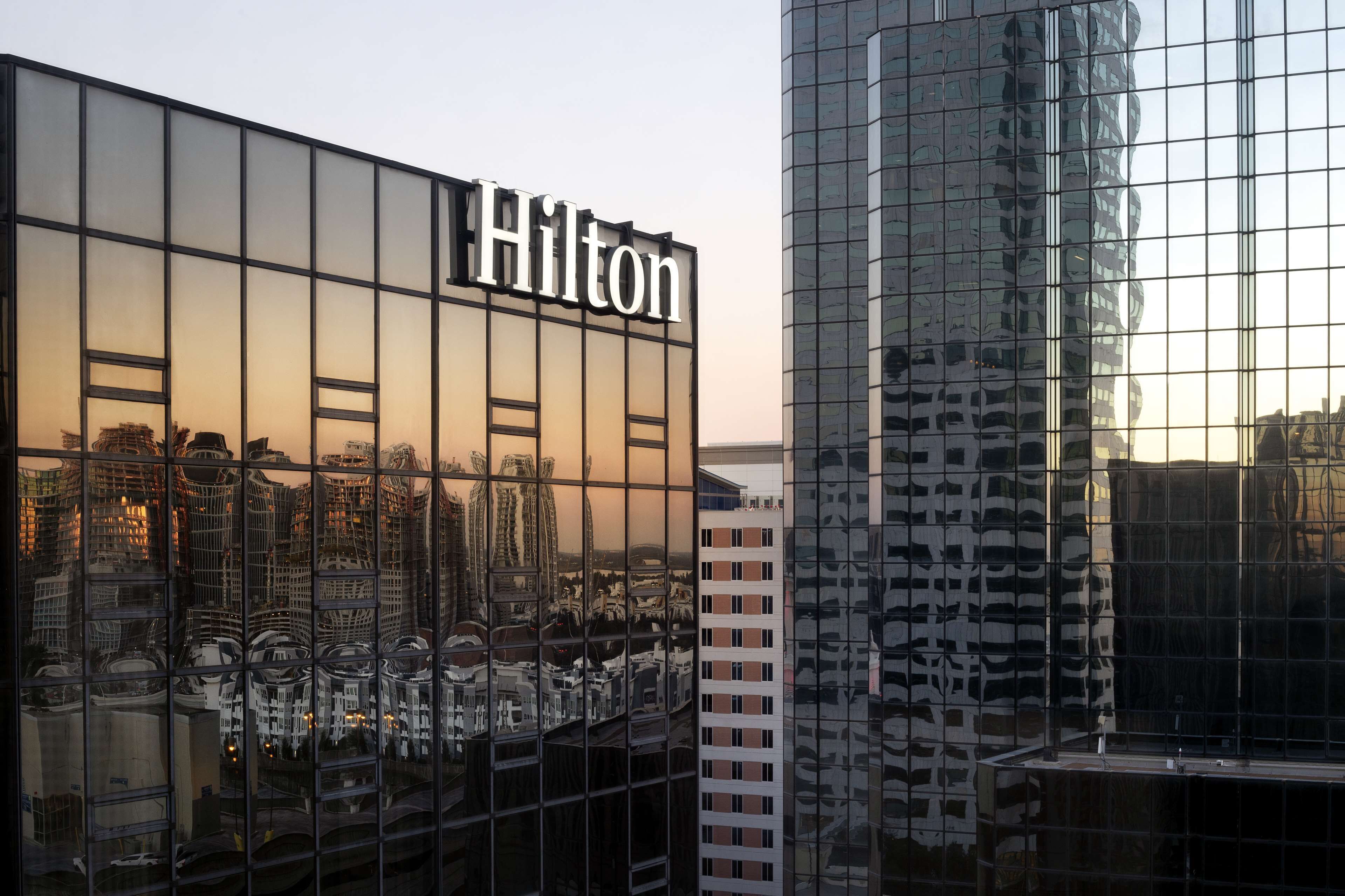 Edificio de un hotel Hilton con fachada de vidrio moderna que refleja el paisaje urbano.