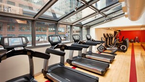 A gym with treadmills, elliptical machines, and a red wall.