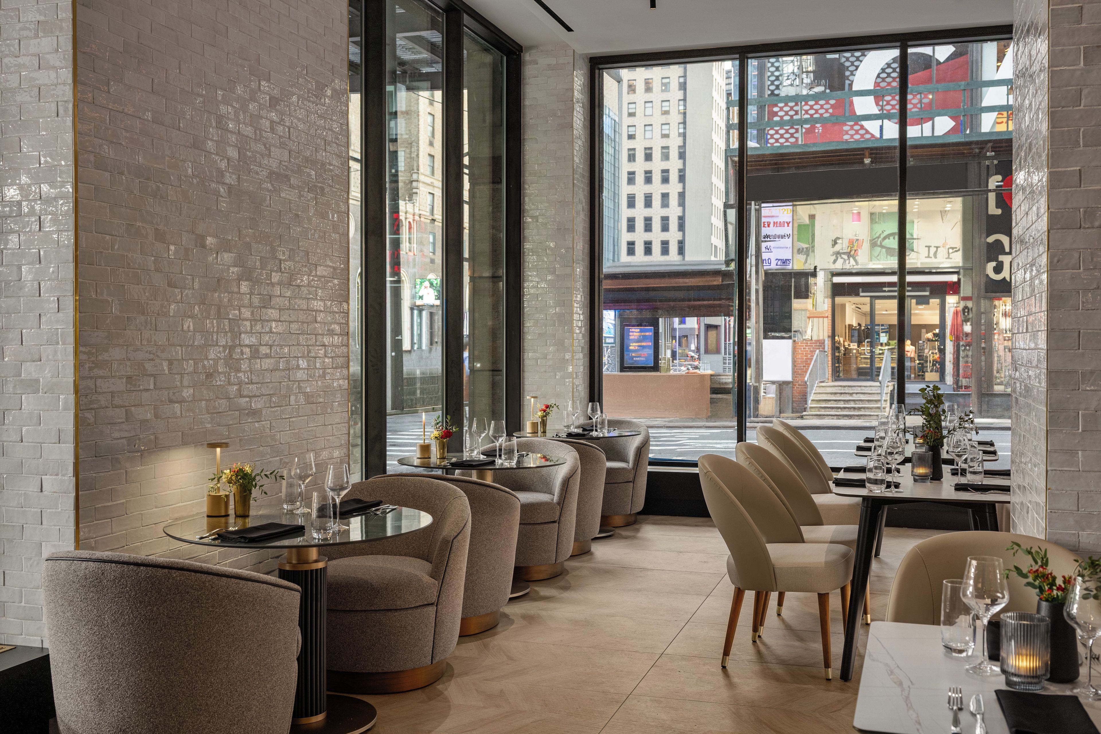 A modern restaurant interior with brick walls, large windows, and a view of the city.