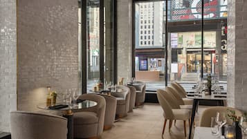 A modern restaurant interior with brick walls, large windows, and a view of the city.
