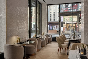 A modern restaurant interior with brick walls, large windows, and a view of the city. - Crowne Plaza Manhattan Times Square by IHG (New York)