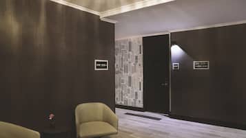 A hotel lobby with a modern design, featuring a cityscape wall, a reception desk, and seating areas.