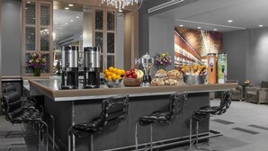 A modern kitchen with a bar area, stainless steel appliances, and a chandelier. - The Manhattan at Times Square (New York)