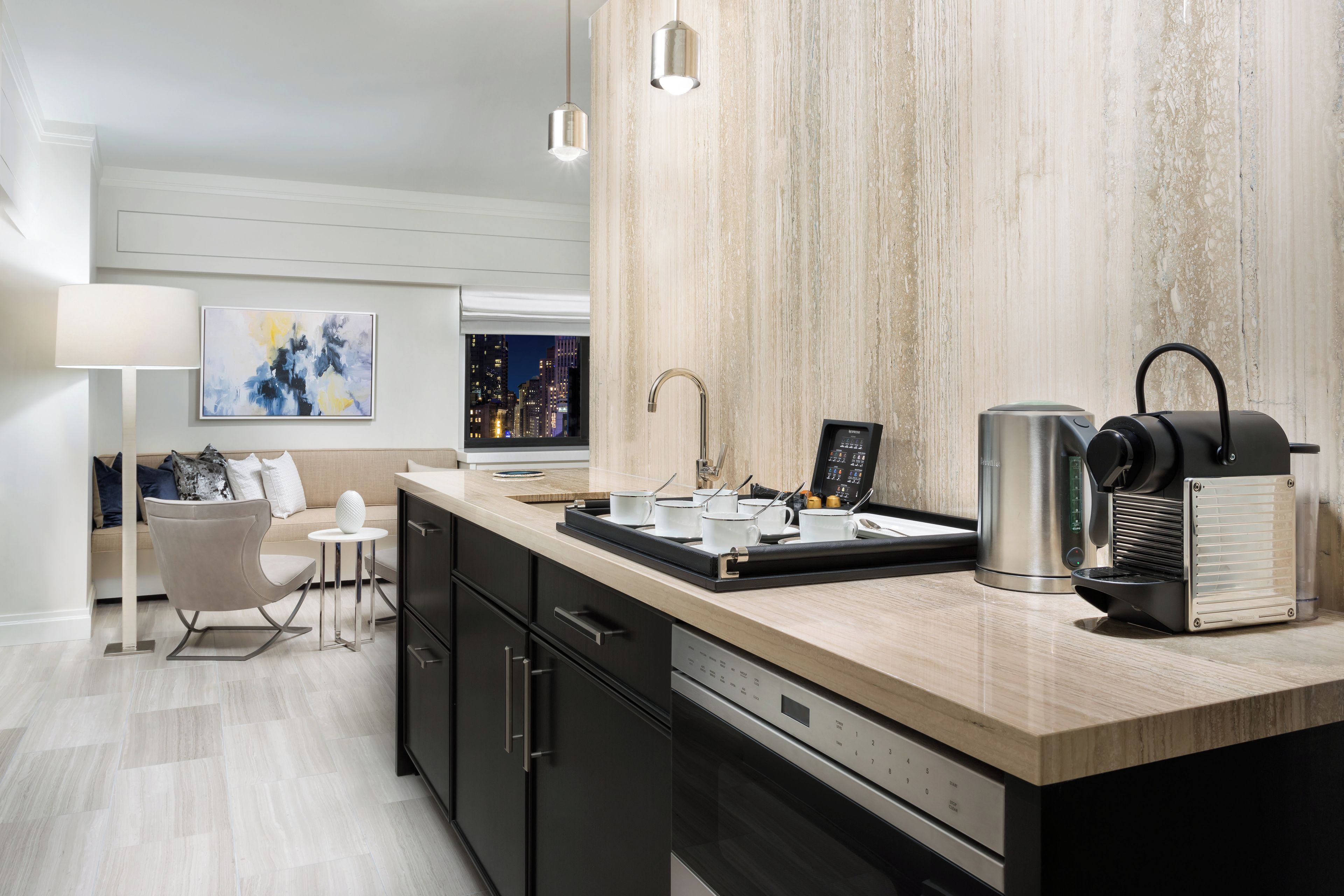 A modern kitchen with a built-in coffee machine, a kettle, and a coffee press on the counter.