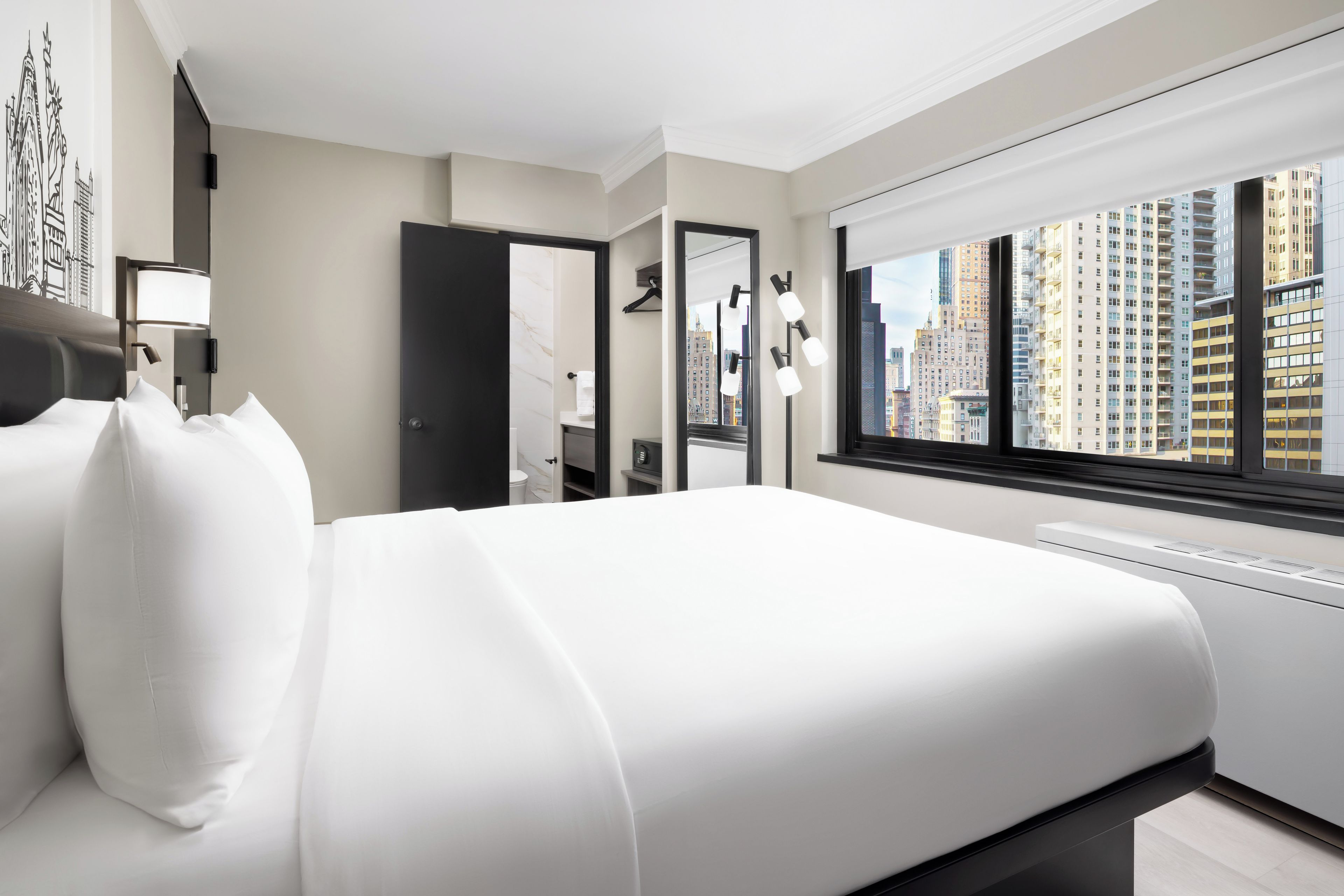 Een moderne hotelkamer met een groot bed, een badkamer en uitzicht op de stad.