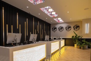 A reception area with a modern design, featuring a reception desk, multiple computer monitors, and decorative wall clocks.