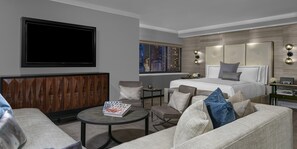 A modern hotel room with a large bed, a seating area with a coffee table, a television, and a city view. - Crowne Plaza Manhattan Times Square by IHG (New York)