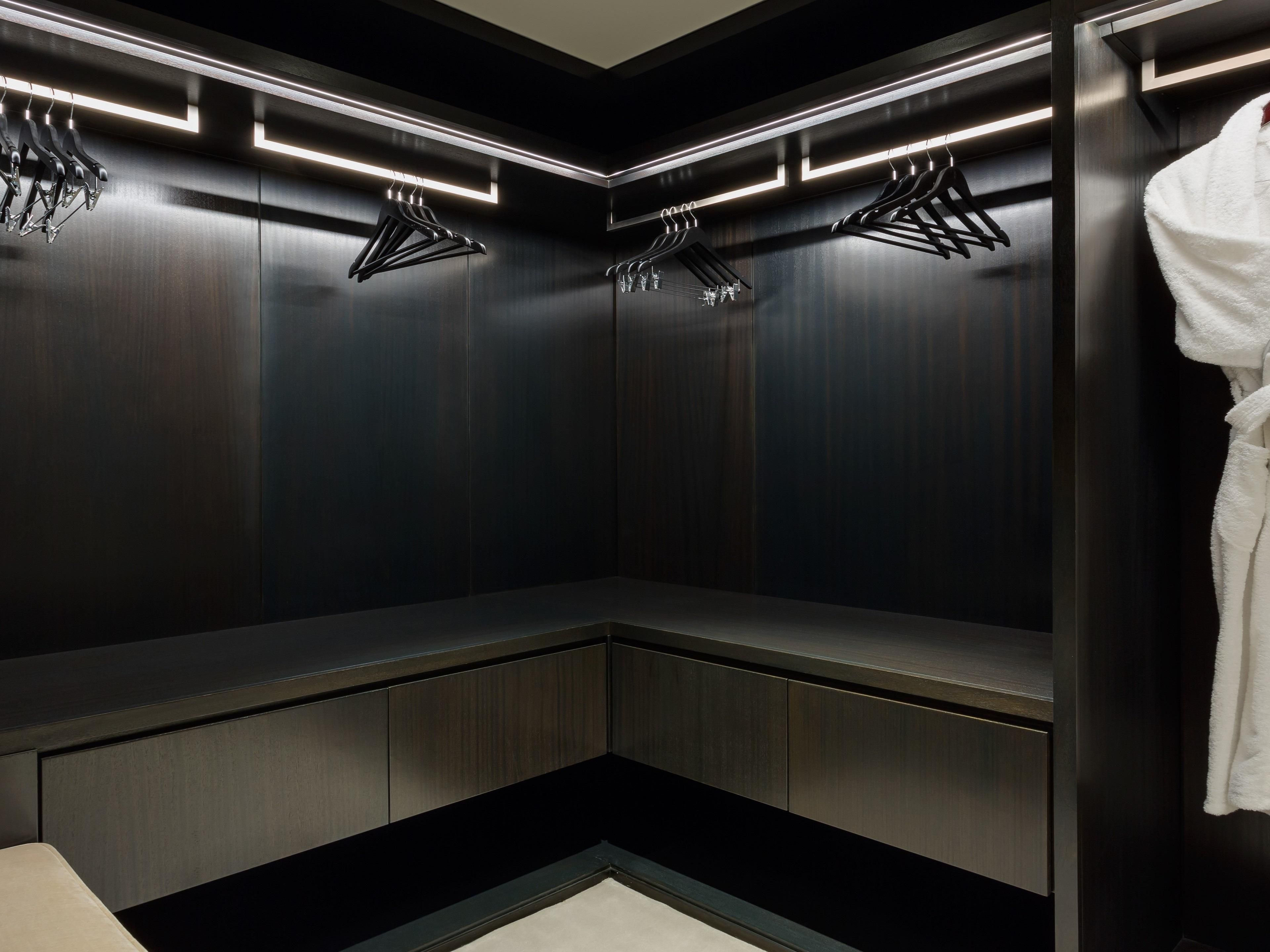A modern, dark-toned locker room with built-in benches and hanging clothes racks.