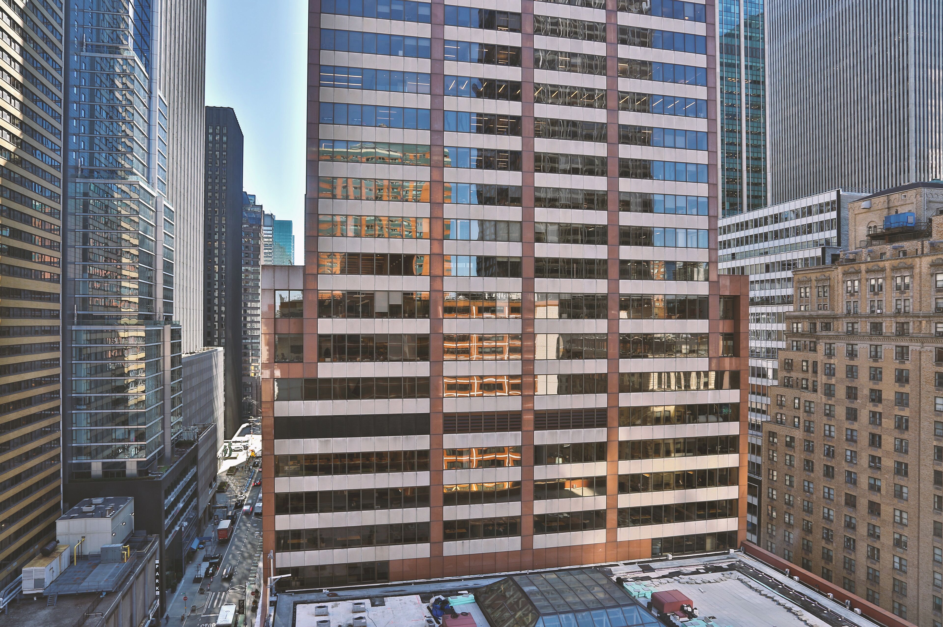 A high-rise building with a grid of windows, surrounded by other tall buildings.