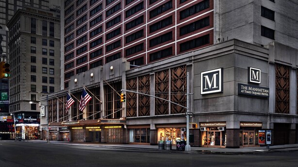 Um hotel com um logotipo 'M' em destaque, letreiros com o nome 'The Manhattan at Times Square Hotel' e fachadas em estilo Americano Craftsman.