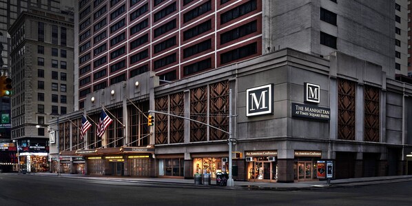 A hotel with a prominent 'M' logo, 'The Manhattan at Times Square Hotel' signage, and 'An American Craftsman' storefronts. - The Manhattan at Times Square (New York)
