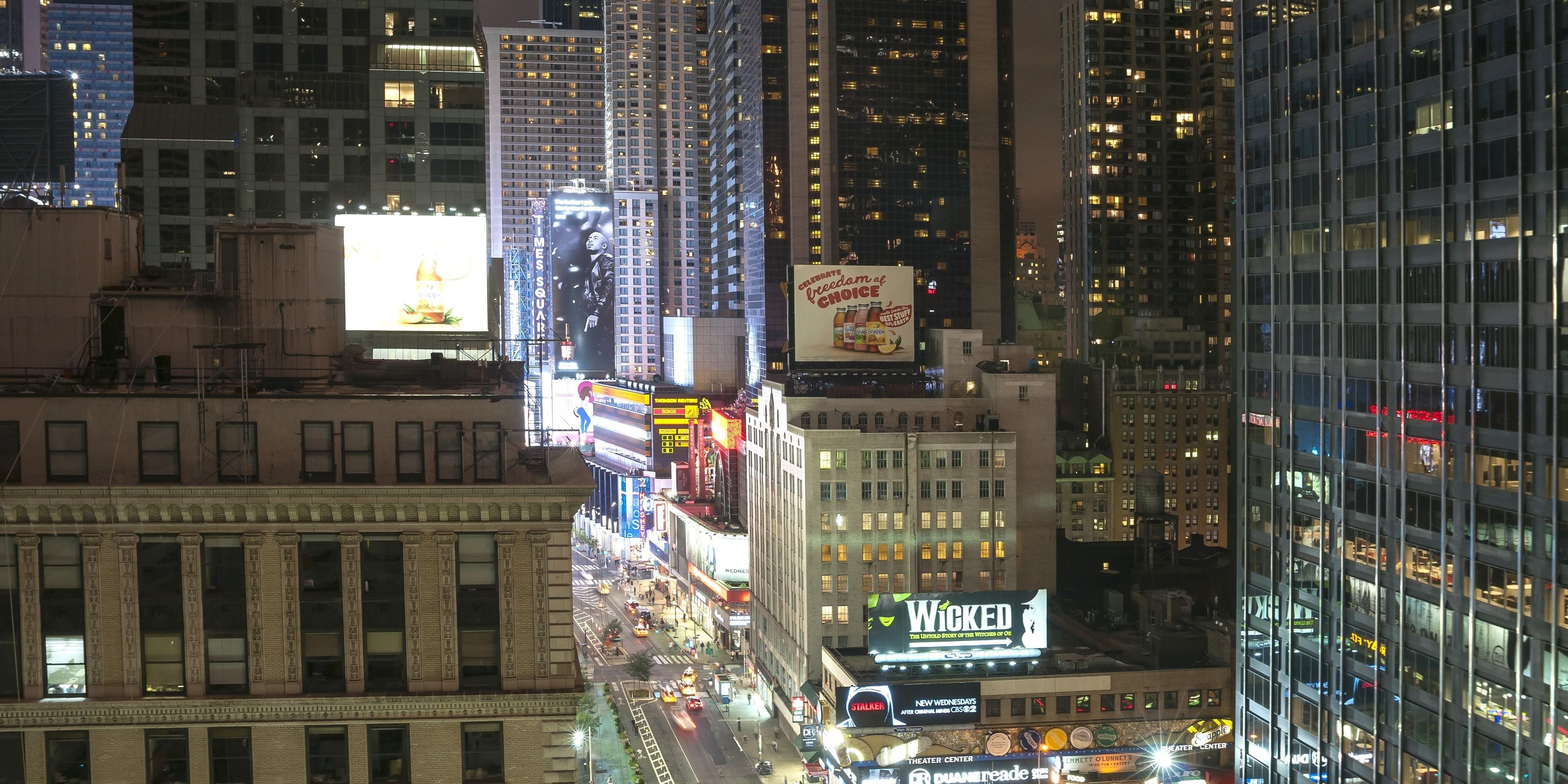 A nighttime cityscape with illuminated billboards and buildings.