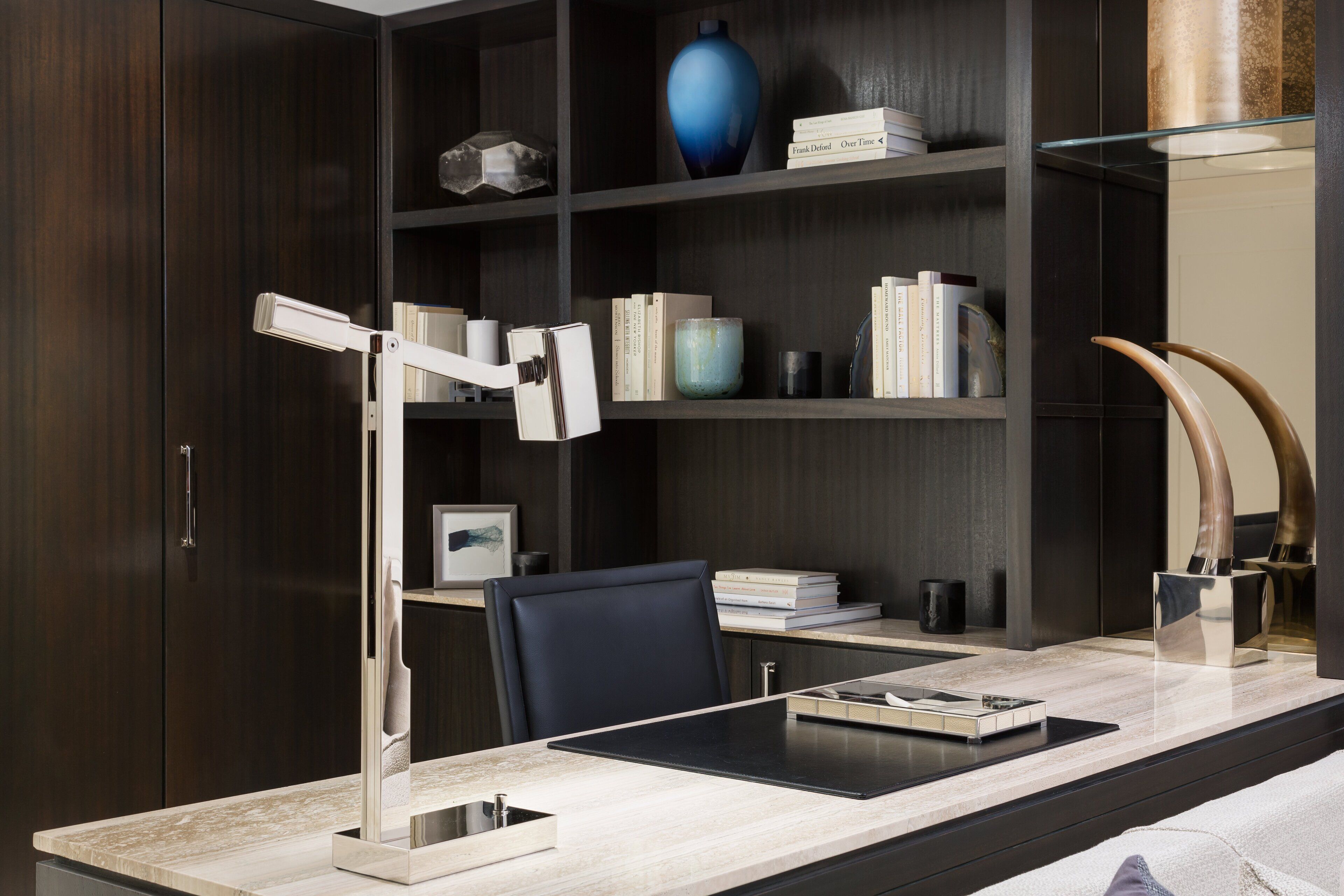 A modern office desk with a desk lamp, a chair, and a glass-top table.