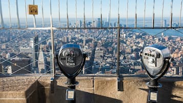 Two vintage coin-operated telescopes with a cityscape view in the background.