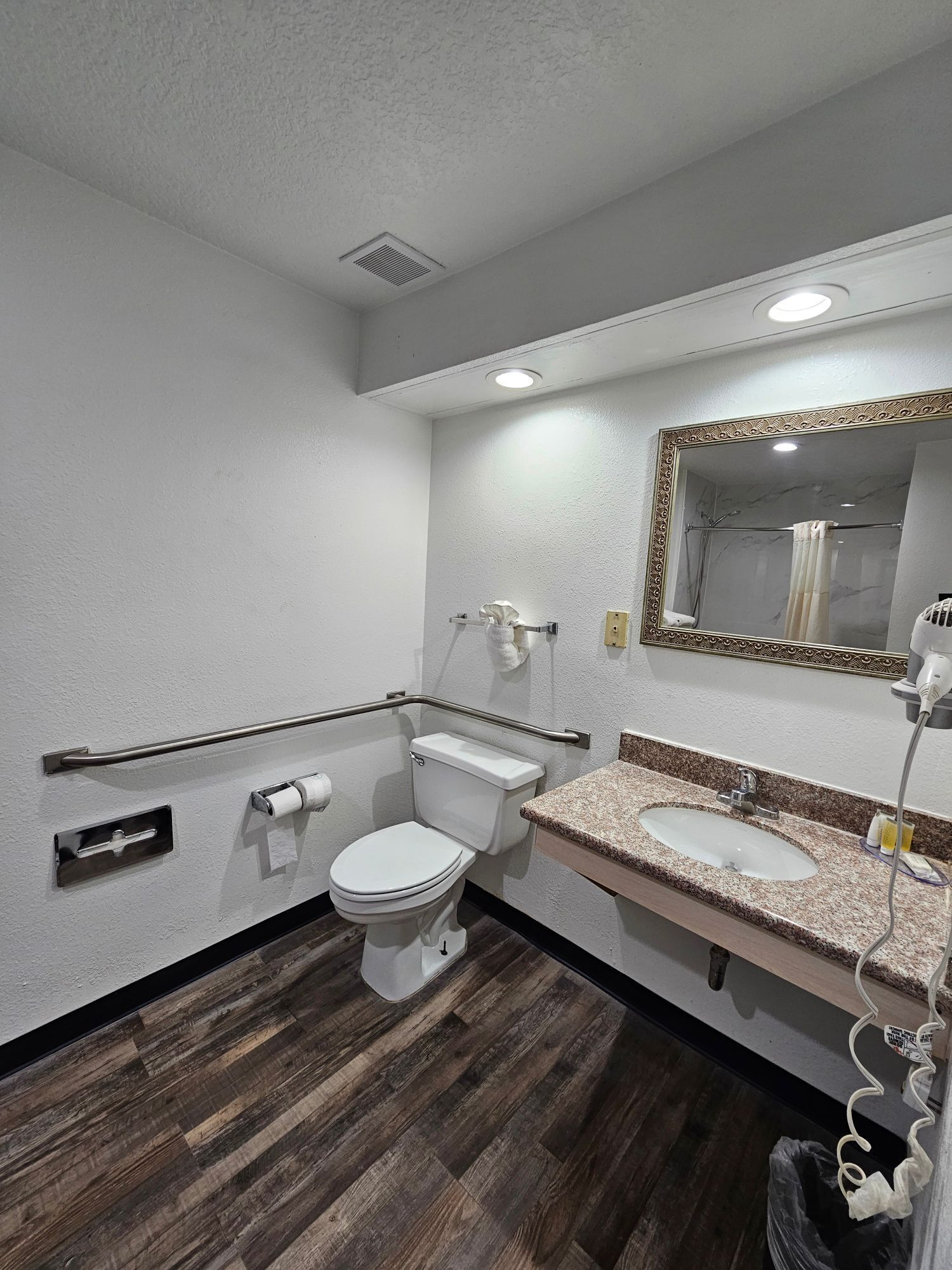 Un baño con inodoro, lavamanos, espejo y secador de manos.