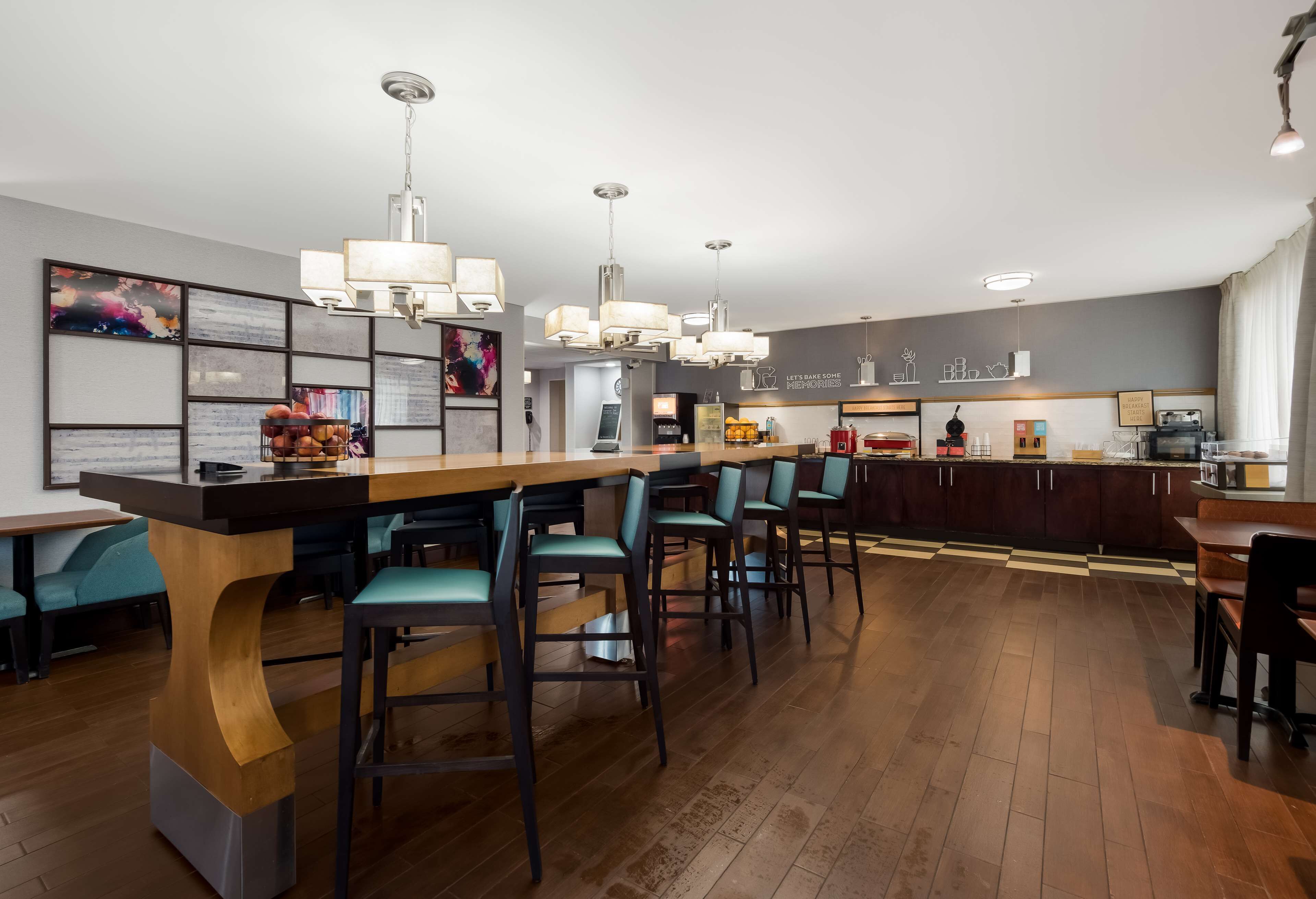 A modern kitchen with a central island, bar stools, and pendant lighting.