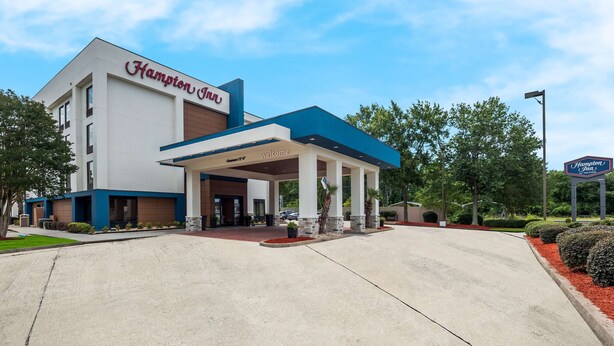 A Hampton Inn hotel with a modern design, featuring a covered entrance and a clear sky.