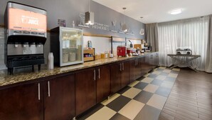A modern kitchen with a juice dispenser, refrigerator, and a coffee machine.