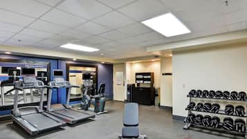 A gym with treadmills, a bench, and a rack of dumbbells.