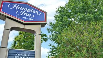 Letrero de Hampton Inn by Hilton con el lema 'Happiness Guaranteed'.