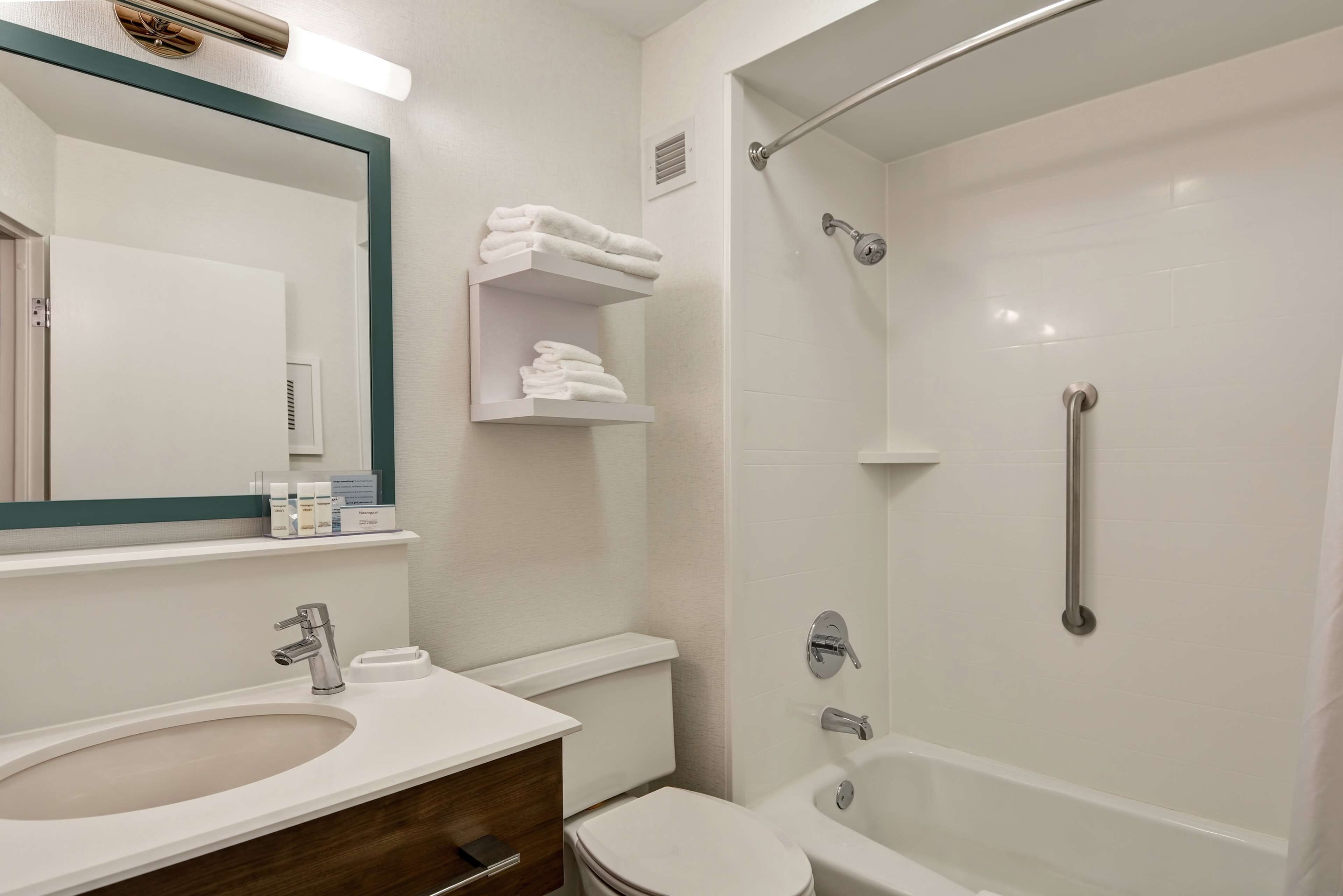A modern bathroom with a sink, toilet, and shower. There are shelves with towels and toiletries.