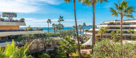 A resort with multiple-story buildings, palm trees, and a view of the sea.