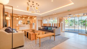 A modern hotel lobby with a reception desk, seating area, and large windows offering a view of the outdoors. - Holiday Inn Nice-Port St Laurent by IHG (Saint-Laurent-du-Var)