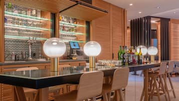 Un área de bar moderna con una barra alargada, varios taburetes y una amplia variedad de botellas de licor.