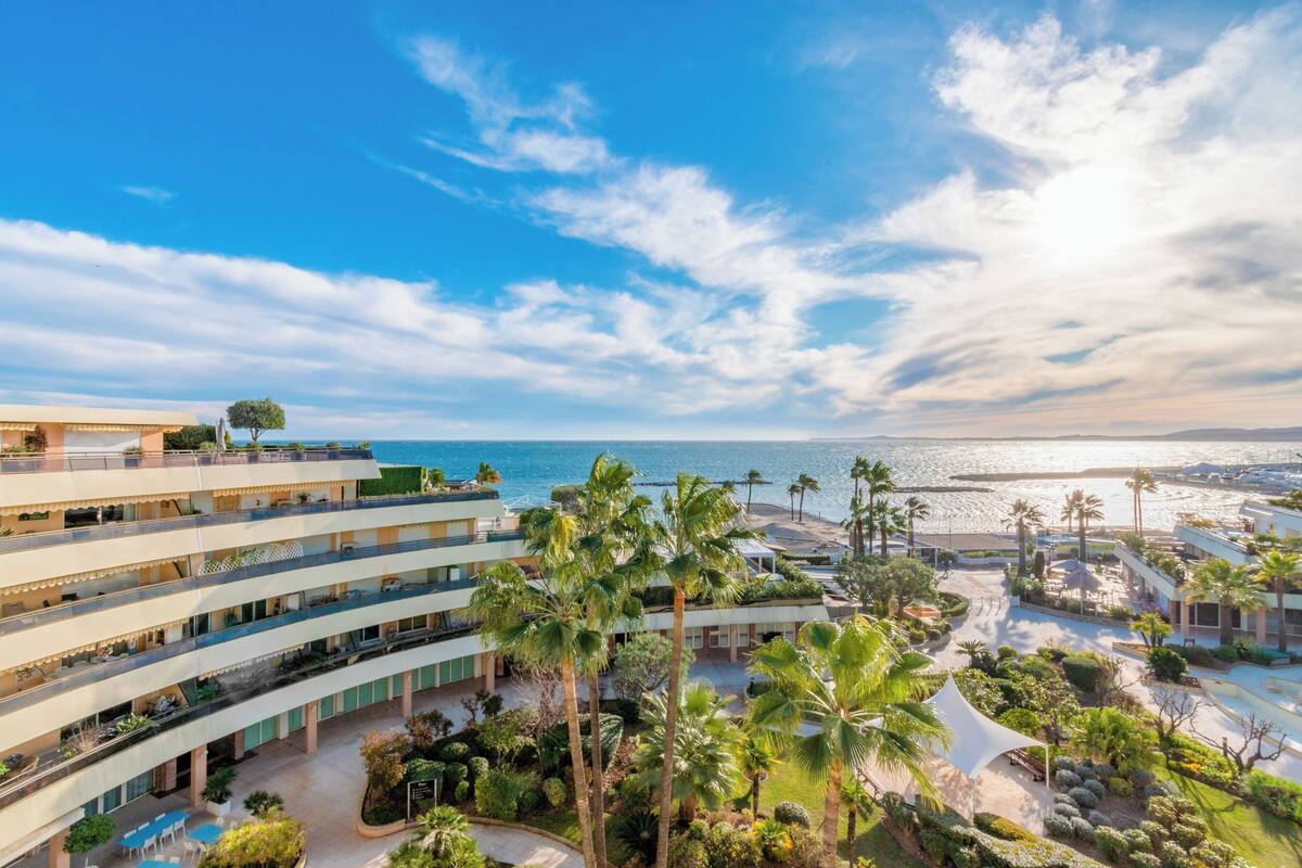 A hotel with multiple floors, outdoor pools, and a view of the sea.