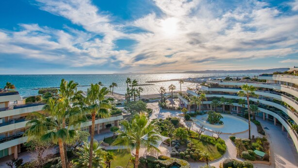 A resort with multiple balconies, palm trees, and a view of the sea. - Holiday Inn Nice-Port St Laurent by IHG (Saint-Laurent-du-Var)