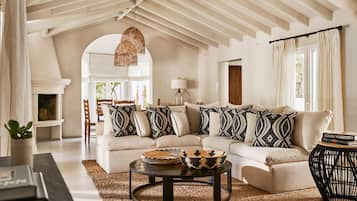 A living room with a sectional sofa, a coffee table, and a hanging light fixture.