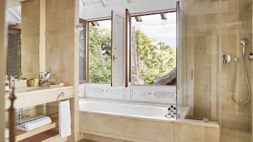 Un baño moderno con una bañera grande, una ducha con cerramiento de vidrio y vistas al exterior.
