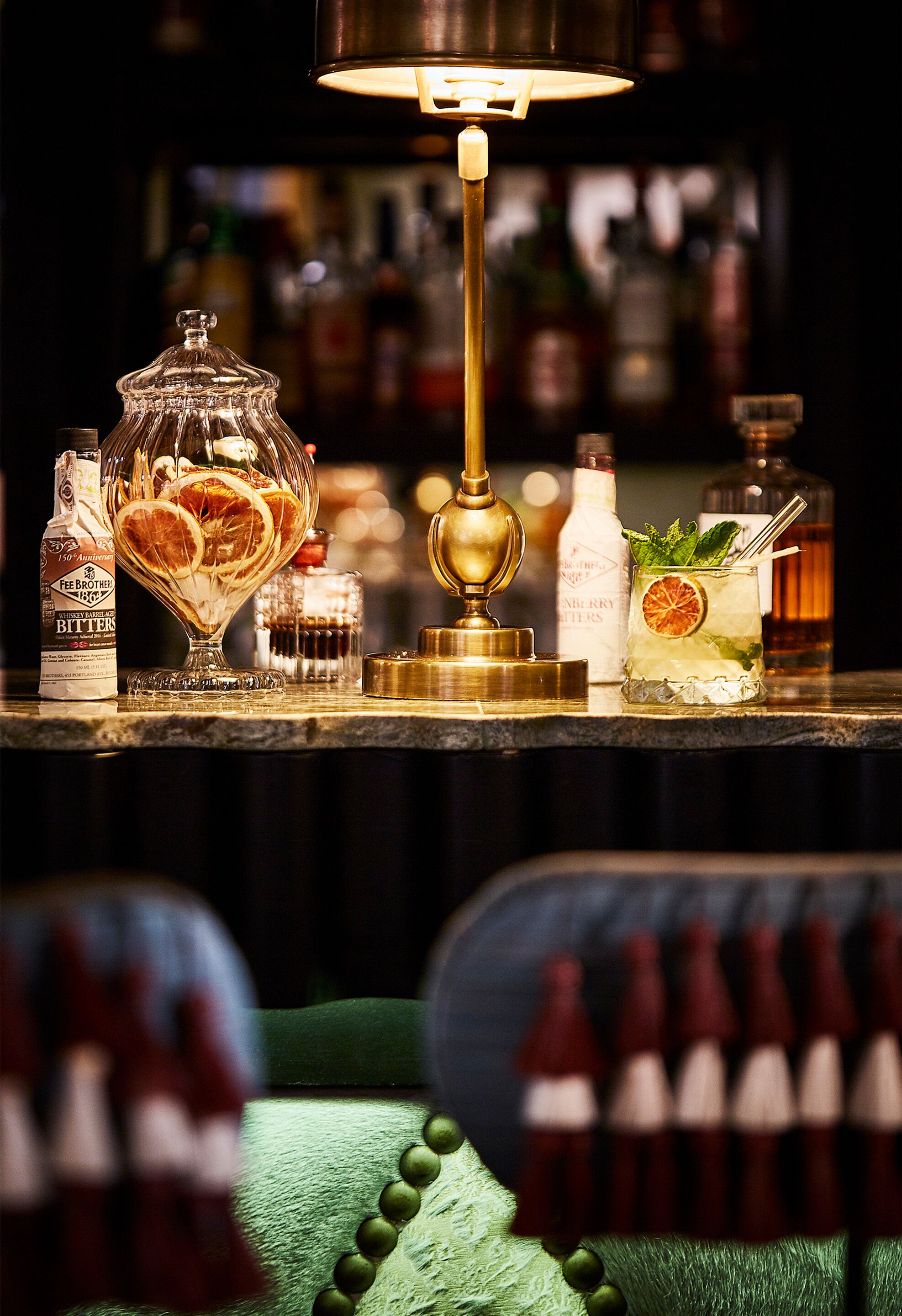 A bar area with a glass decanter, bottles, and a cocktail glass with a garnish.